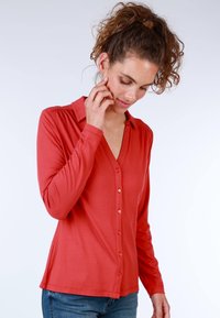 Red button-up shirt with a collar, long sleeves, soft texture, slight gathering at shoulders, and contrasting buttons.