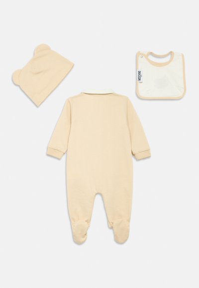 Φωτεινό μπεζ βρεφικό φορμάκι με μακριά μανίκια και σχέδιο που καλύπτει τα πόδια. Συνοδεύεται από καπέλο με αυτιά αρκούδας στο ίδιο χρώμα και Bib κρεμ.