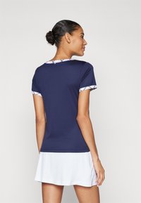 Camisa deportiva de color navy con mangas cortas, que presenta un ribete en blanco y azul alrededor del cuello y las mangas, tela suave y diseño ajustado.