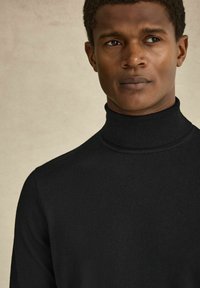 Mustat korkeakauluksiset neulepaidat, jotka on valmistettu hienosta neuloksesta, korkea kaulus ja tiukka istuvuus, sileä pinta ja ei näkyviä kuvioita.