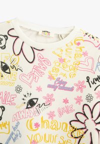 Sudadera de forro polar en crema con estampados multicolores y divertidos que incluyen flores, ojos y texto en amarillo, rosa y negro. Cuello de canalé.