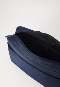 Marineblauwe laptoptas met een gestructureerde buitenkant, ritsluiting en zwarte binnenkant. Voorzien van een kleine riem om de inhoud veilig te stellen.