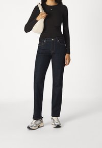 Tmavě modré džínové kalhoty s rovnými nohavicemi, vysokým pasem, kontrastním prošíváním a malým logem na kapse.