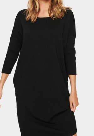 Robe en tricot noir avec un décolleté carré, des manches trois-quarts et une coupe décontractée. Le tissu est lisse, offrant une texture douce.