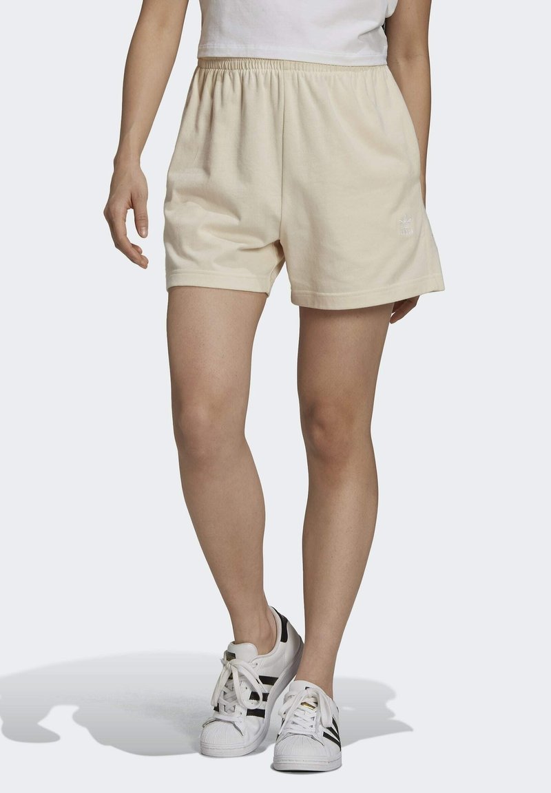 Beige bomullsblandning-shorts med elastisk midja, med en minimalistisk design och broderad logotyp. Kombineras med vita sneakers.