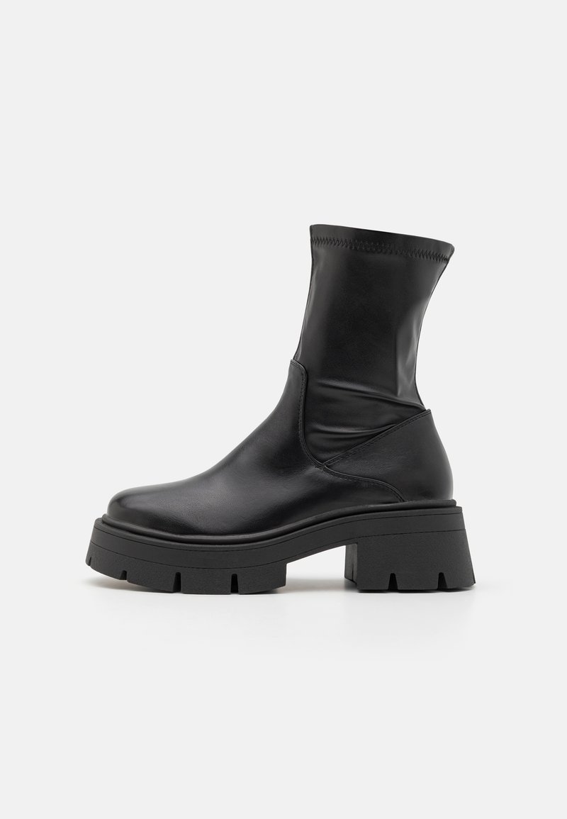 Botte en cuir noir mi-mollet avec semelle à crampons épaisse et petit talon bloc, dessus lisse avec détail cousu près de la cheville.