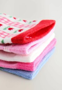 Sæt med fem strikkede sokker i forskellige farver: rød, pink, hvid og lyseblå. Har en rød detalje øverst og blomsterprint på en af sokkerne.