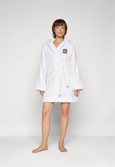 White terry robe with a hood, belted waist, and two front pockets. Features a brown bear logo and spacious, wide sleeves.