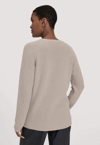 Hellbeige Pullover mit gerippter Textur, runder Ausschnitt und langen Ärmeln; bietet eine lockere Passform und einen längeren Rücken.