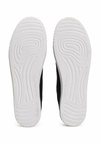 Scarpe sportive nere con tomaia in rete testurizzata e suola in gomma bianca con motivo a onde e logo del marchio impresso sui lati.