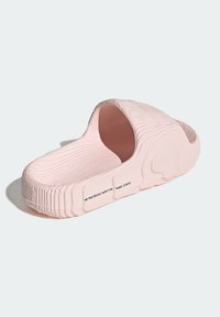 Rosa slip-on sandal med en texturerad yta, öppen tå och sidokutt. Har en upphöjd räfflad design och varumärke på sidan.