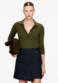 Olive green ribbed long-sleeve polo shirt with button closure paired with a dark denim A-line skirt featuring a button accent and front slit.