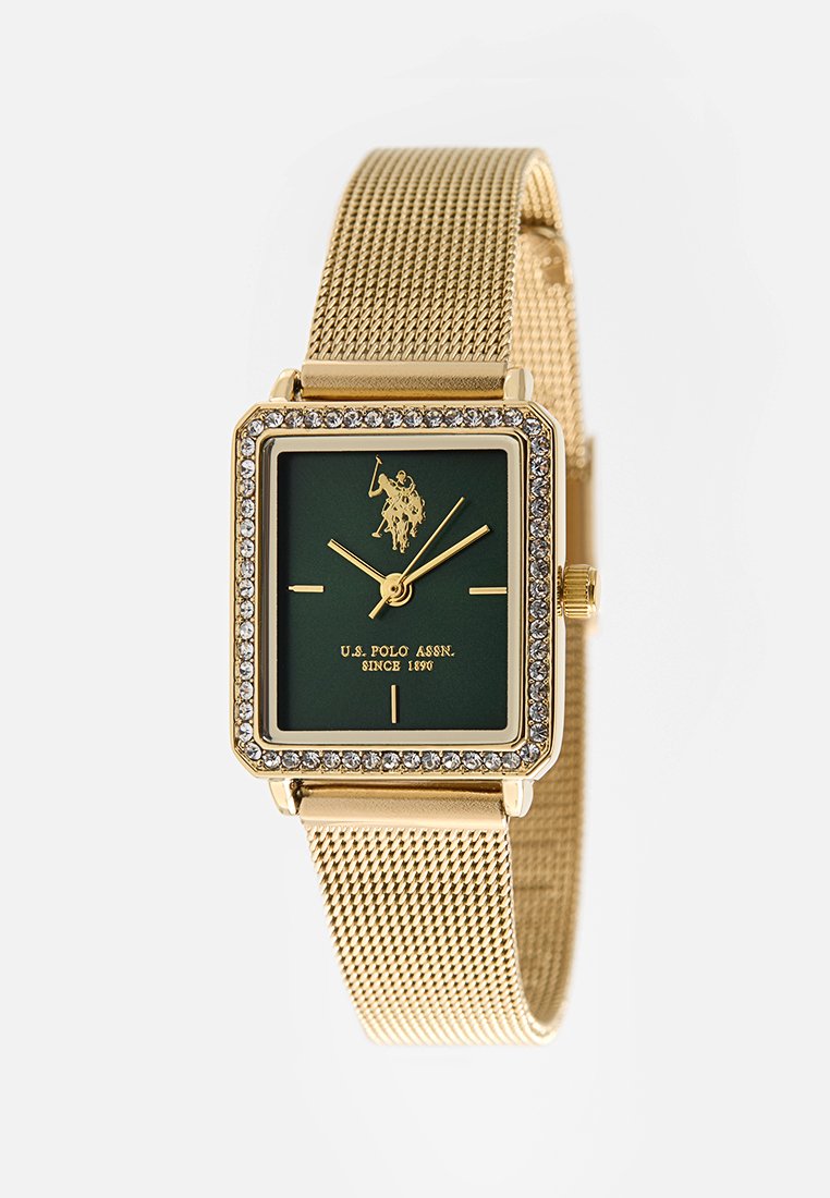 Montre carrée dorée avec un cadran vert, accents de cristal et bracelet en maille. Comprend des aiguilles dorées et un logo sur le visage.