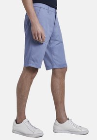 Shorts azzurri, in cotone, lunghezza al ginocchio, con tasche frontali e vita. Abbinati a sneakers bianche.