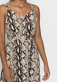 Ärmlös klänning med V-ringning, med ett mönster av beige och svart ormtryck. Tillverkad av ett lätt tyg med en avslappnad passform.