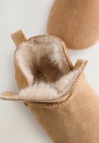 Stivali alla caviglia in suede color beige con una morbida foderatura in pelliccia, caratterizzati da un design pieghevole e cuciture texture lungo i bordi.