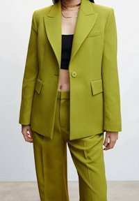 Limoengroene op maat gemaakte pak met een gestructureerde blazer met inkeping revers en twee voorzakken, gecombineerd met bijpassende broek in een gladde stof.