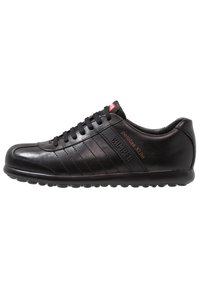 Black leather sneaker with a rounded toe, lace-up design, horizontal stitching accents, and a textured side panel with logo detailing.