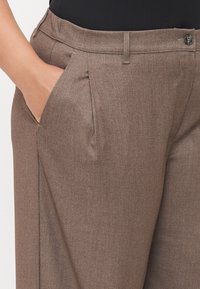 Brown, textured dress trousers featuring a relaxed fit, front pockets, and subtle pleats, complemented by a button closure at the waistband.