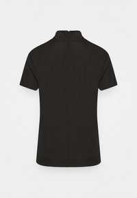 Svart kortärmad skjorta med hög krage och dragkedja bak. Slät tyg, enkel design och inga mönster eller detaljer i metall synliga.