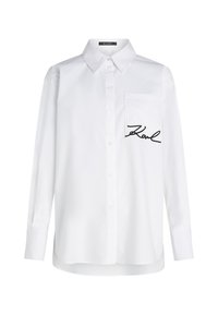 Hvit skjorte med spiss krage, lange ermer og en venstre brystlomme med svart brodert tekst "Karl." Glatt tekstur.