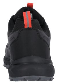 Schwarze Sportschuhe mit einer strukturierten Oberseite, kontrastierenden roten und grauen Akzenten, einer robusten Gummisohle und einer Zuglasche auf der Rückseite.