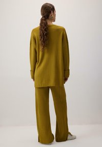 Sinepik ribakudumi pikk sviiter ja laiad püksid komplekt. Kangas omab tekstuurset välimust, külgmiste lõigetega ja laia lõikega.