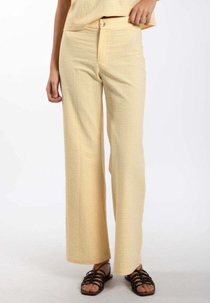 Pantalons taille haute rayés jaune et blanc avec une coupe ample, dotés d'une fermeture à bouton et d'un tissu texturé.