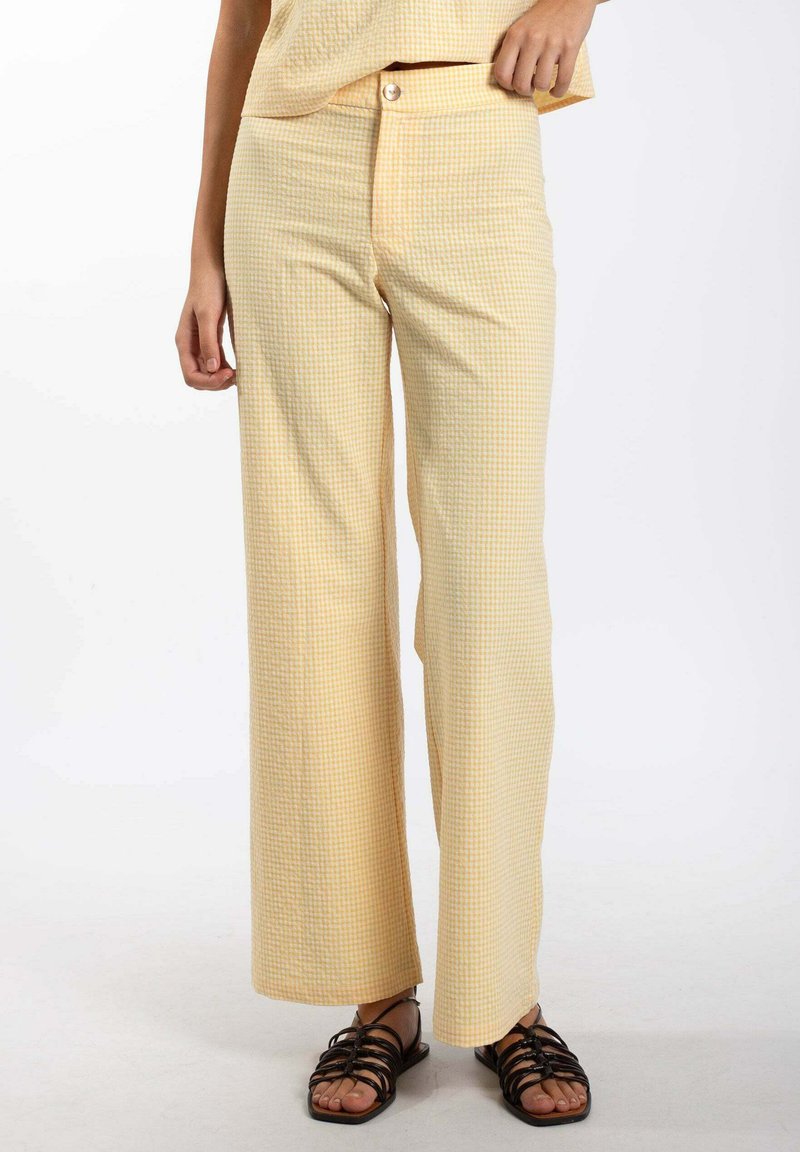 Pantalones de cintura alta a cuadros amarillos y blancos con un diseño de pierna ancha, que cuentan con un cierre de botón y una tela texturizada.