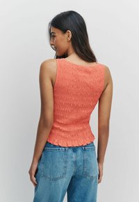 Korallivärviline kinnitusdetailidega siidriietusega top, millel on keha ümbritsev lõige, narmendav äär ja varrukateta lõige. Kandmiseks koos helesiniste, kõrge vöökohaga teksapükstega.