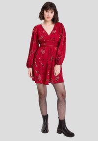 Red floral dress with long puff sleeves, fitted waist, and a flared skirt. Worn with black fishnet tights and chunky black ankle boots.