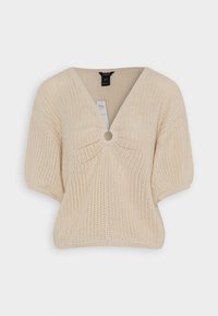 Haut en tricot beige avec un col en V, des manches courtes et un accent circulaire au centre. Présente un motif en rib texturé sur l'ensemble.