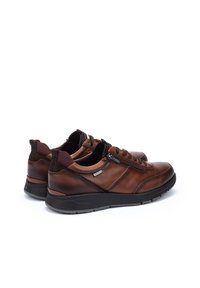 Zapatillas de cuero marrón con un acabado texturizado, cierres de cordones y cremallera, acentos en burdeos contrastantes y una suela de goma negra.