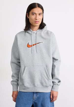 Grå huvtröja i mjukt material, med en orange Nike-logotyp, framficka och ribbade mudd och fåll.