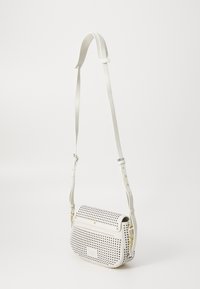 Borsa a tracolla in materiale sintetico bianco con motivo perforato. Cinghia regolabile e dettagli metallici in tono oro. Forma rettangolare con chiusura a patta.