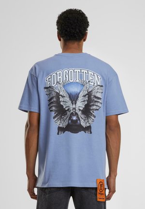 Light blue cotton t-shirt featuring a large graphic of a butterfly and face on the back, with "FORGOTTEN" text above. Orange tag on hem.