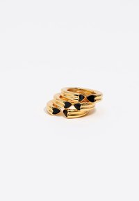 Anillos apilados en tono dorado con acentos en forma de corazón de color negro, acabado liso, diseño curvado y diferentes anchos.