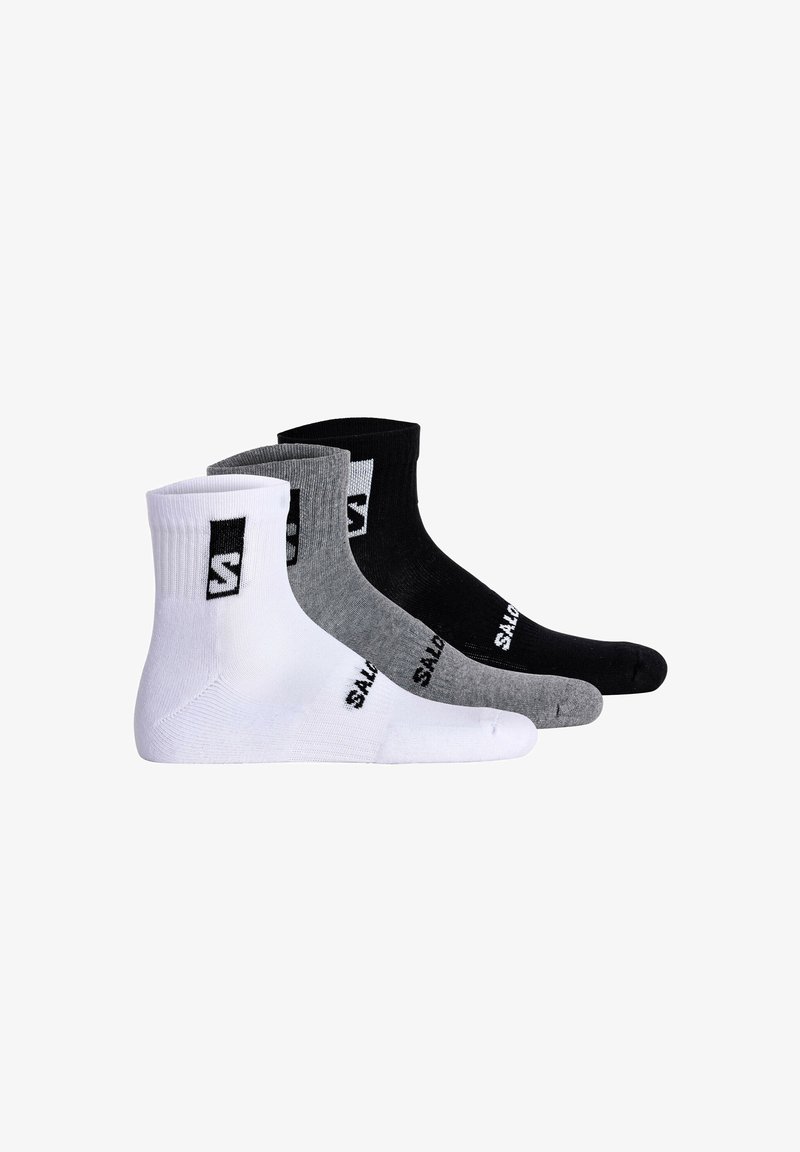 Tres pares de calcetines tobilleros en blanco, gris y negro, con puño acanalado y logo prominente. Hechos de una tela suave y elástica.