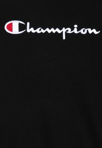Black fabric t-shirt featuring embroidered white "Champion" logo with red accent in the letter "C." Smooth texture, standard fit.
