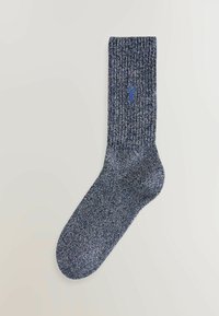 Tamsiai mėlyna megzta kojinė su tekstūruota ribota dizainu. Šone yra mažas mėlynas logotipas. Minkšta medžiaga ir vidutinio ilgio iki blauzdos.