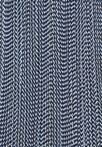 Tende con motivi a zigzag chevron in blu navy e bianco, creando una texture pieghettata sul tessuto.