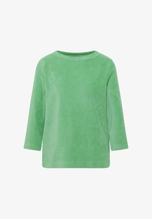 Vihreä corduroypaita pitkillä hihoilla, pyöreällä pääntie-aukolla ja rentouttavalla istuvuudella, esillä valkoista taustaa vasten.