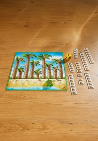 Board game featuring a colorful beach scene with palm trees, a green turtle figure, a yellow die, and multiple tiles with animal graphics.