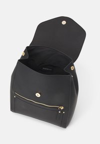 Mochila de imitación de cuero negra con un cierre a presión dorado, bolsillo interior y bolsillo delantero con cremallera. Textura suave, diseño minimalista.