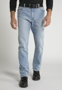 Helle blaue Jeans mit geradem Beinschnitt, ausgestattet mit einem schwarzen Ledergürtel, subtilen Abnutzungsspuren und einem Fünf-Taschen-Design. Schwarze Schuhe runden den Look ab.