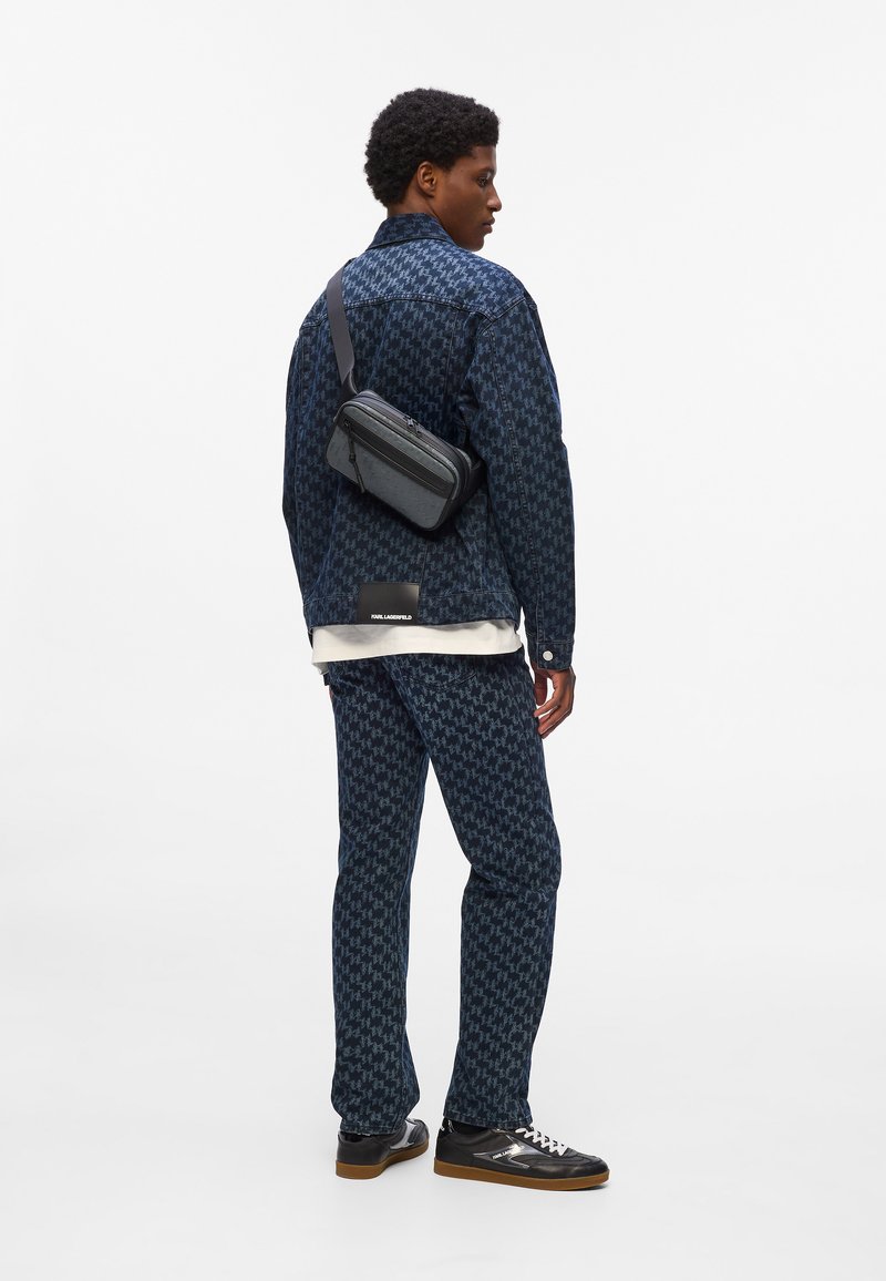Denim jacket and pants in dark blue houndstooth pattern, paired with a black crossbody bag and black sneakers with brown soles.