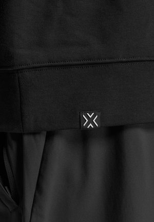 Sort athletic hoodie med et tekstureret stof, ribbet kant og et lille logo-tag med geometrisk design i hvid.
