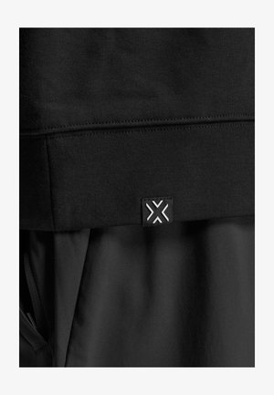 Sort athletic hoodie med et tekstureret stof, ribbet kant og et lille logo-tag med geometrisk design i hvid.