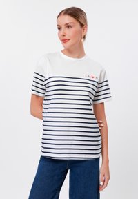 T-shirt rayé en blanc et marine avec manches courtes, col rond et texte "L'AMOUR" en rouge. Tissu en coton doux, coupe décontractée.