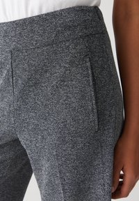 Pantaloni grigi su misura realizzati in un tessuto testurizzato con un motivo sottile, dotati di una vita piatta e dettagli con tasche laterali.